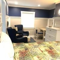 A bedroom with a bed , chairs , dresser and window.