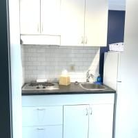 A small kitchen with white cabinets , a sink , stove and refrigerator.