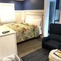 A bedroom with a bed , chair , ottoman and trash can.