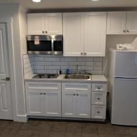 A kitchen with white cabinets , a sink , a microwave , and a refrigerator.