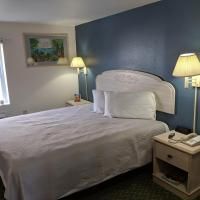 A hotel room with a bed , nightstand , lamps and a picture on the wall.