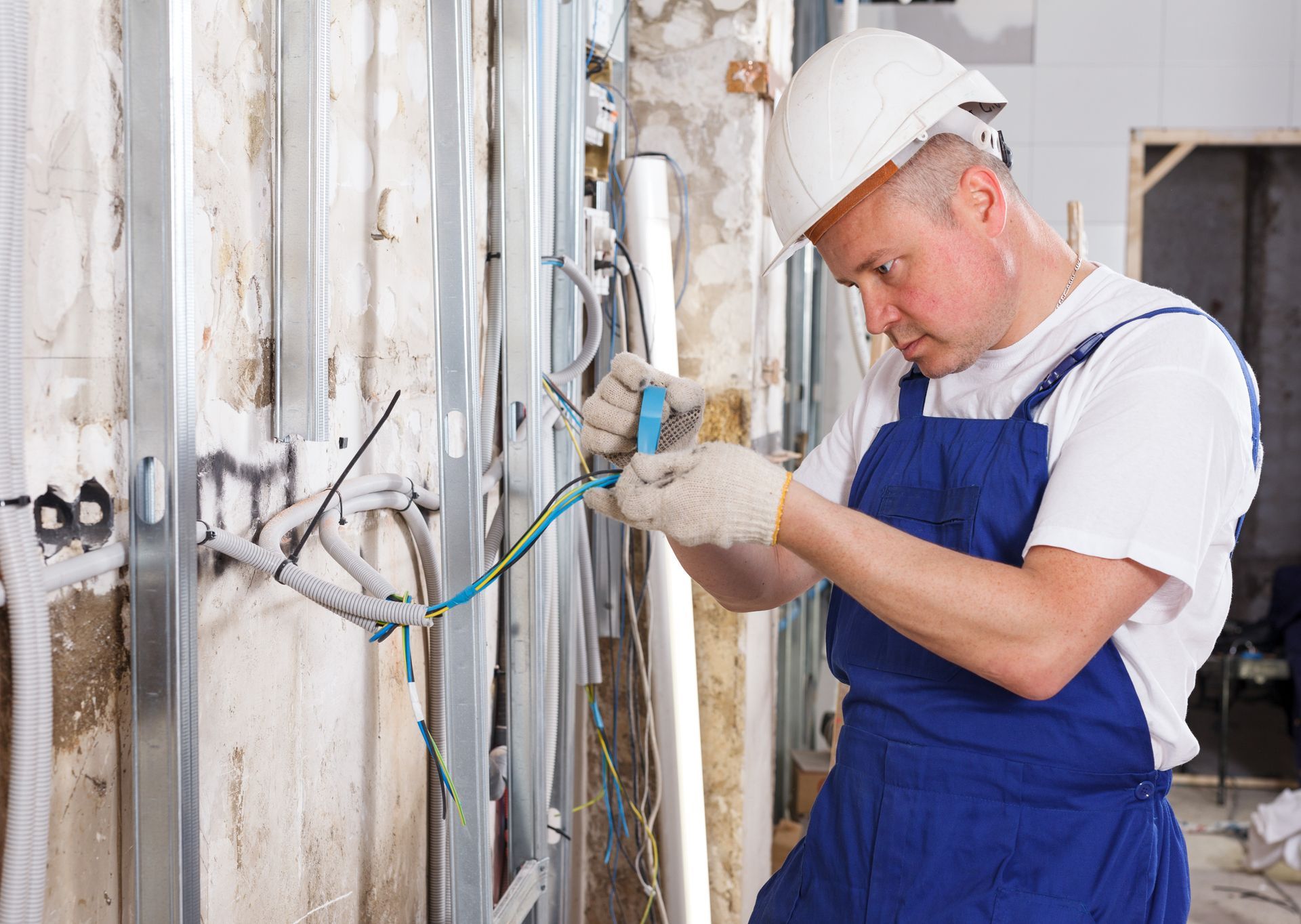 A professional electrician wiring a new home during a project for an expert electrical contractor.