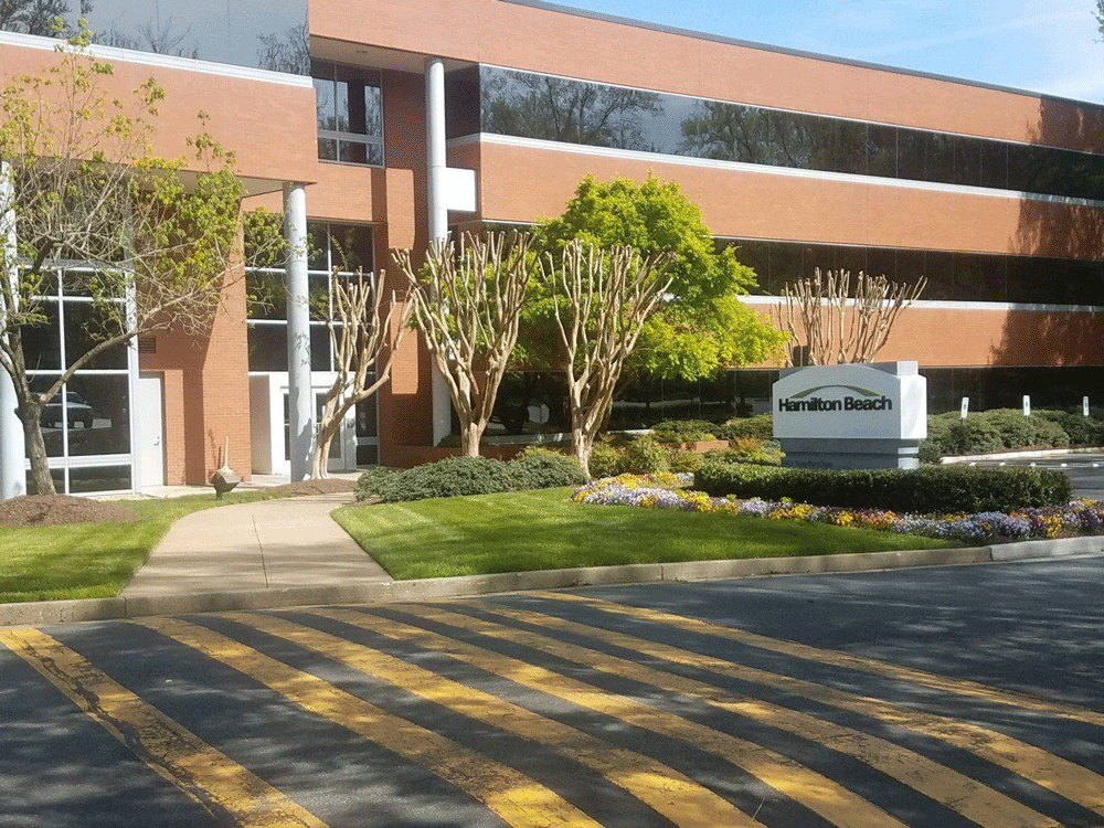 Office building with brick facade, glass windows, and landscaped grounds. 