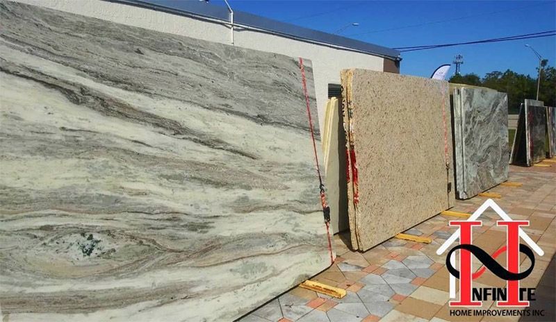 Large stone slabs displayed outdoors on stands in a sunlit yard