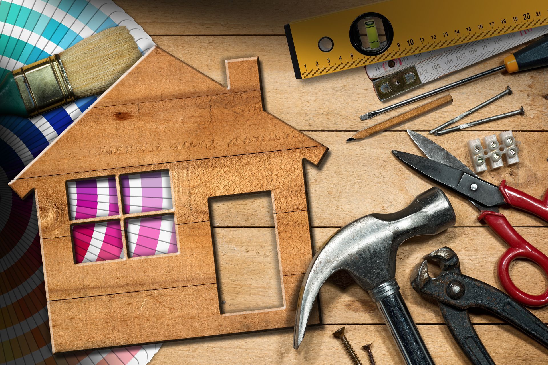 Wooden house outline with tools, paint swatches, and a brush, representing home improvement.