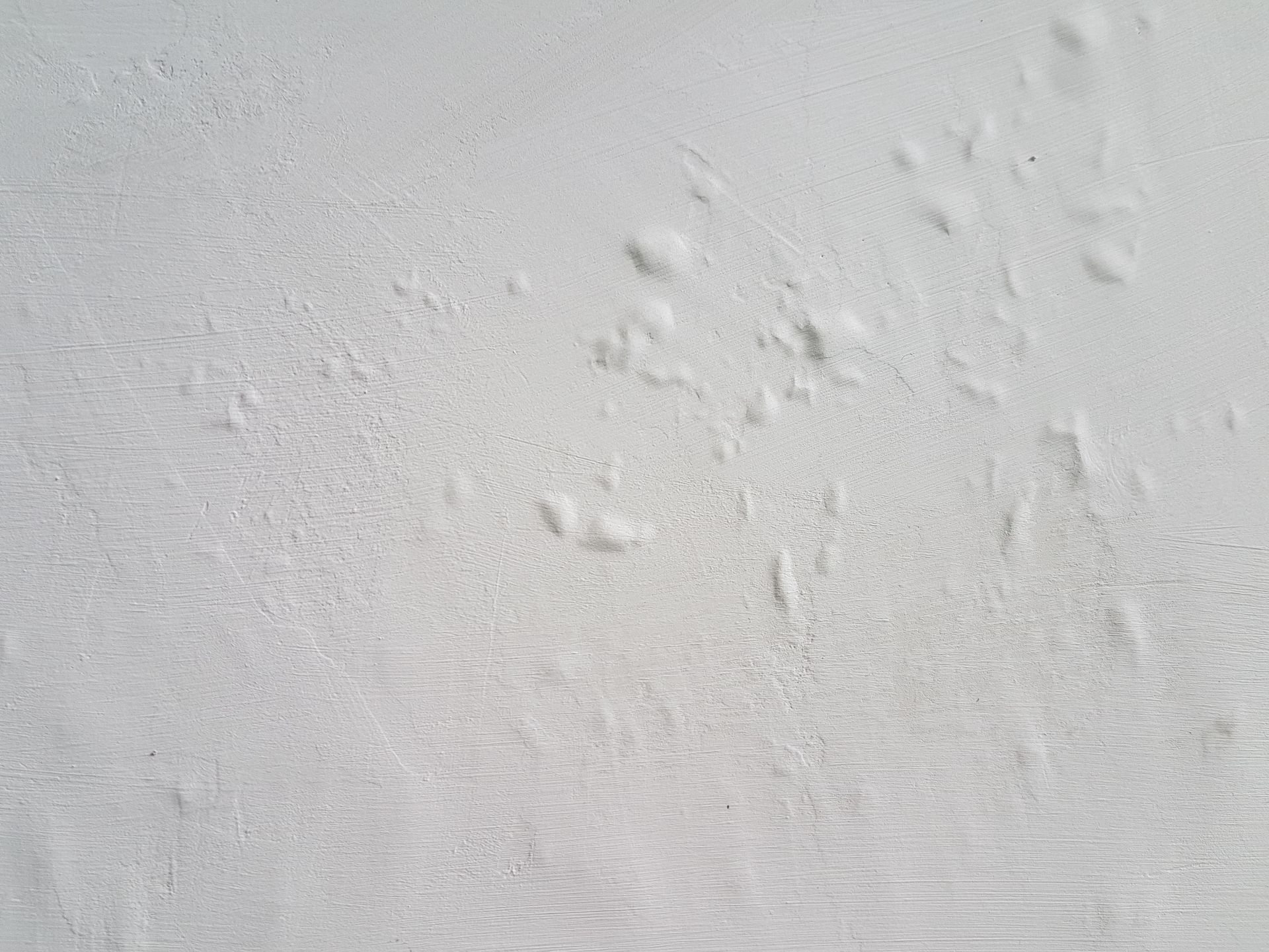 White wall with multiple raised bumps, texture uneven.
