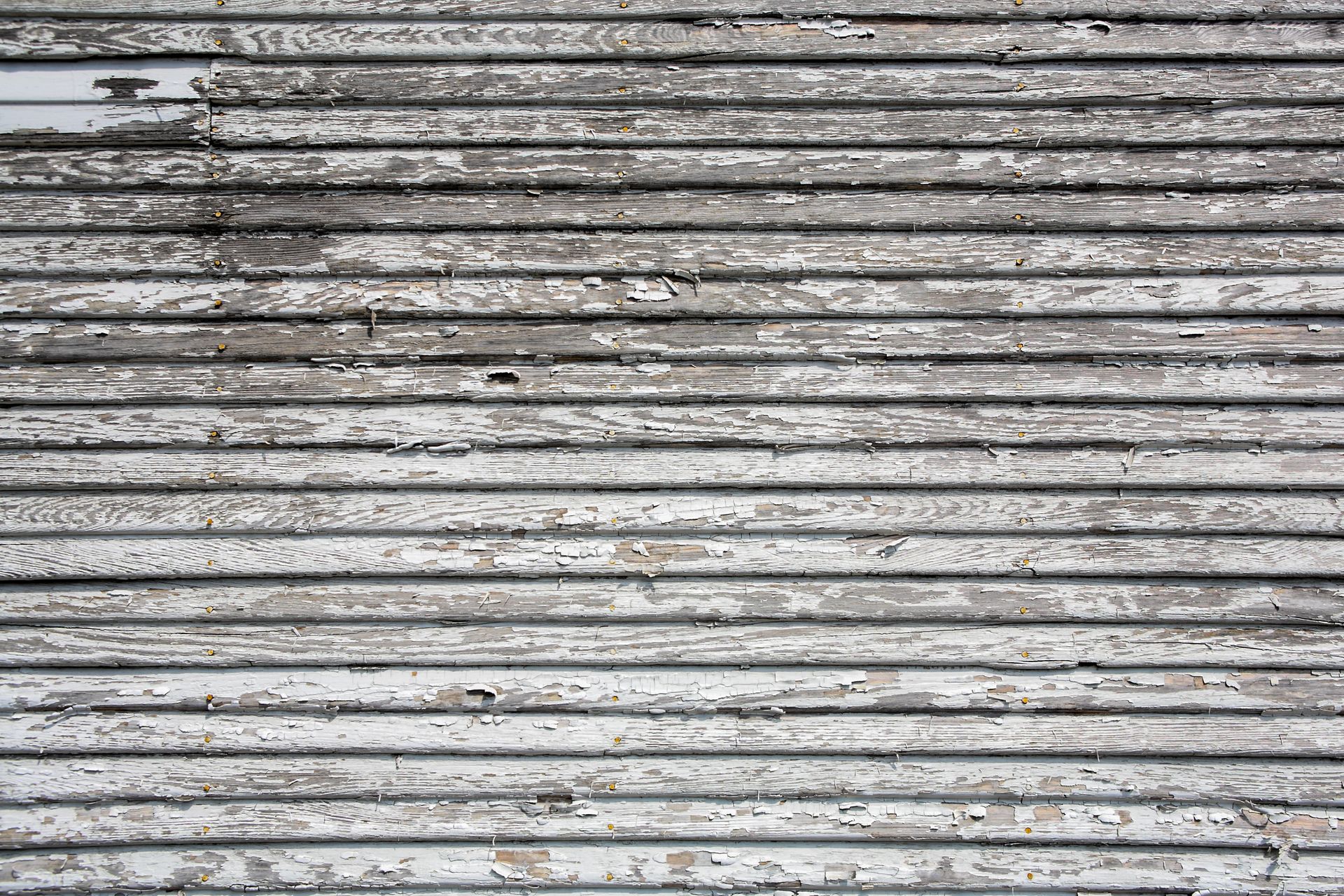 Weathered horizontal white wooden siding, peeling paint.