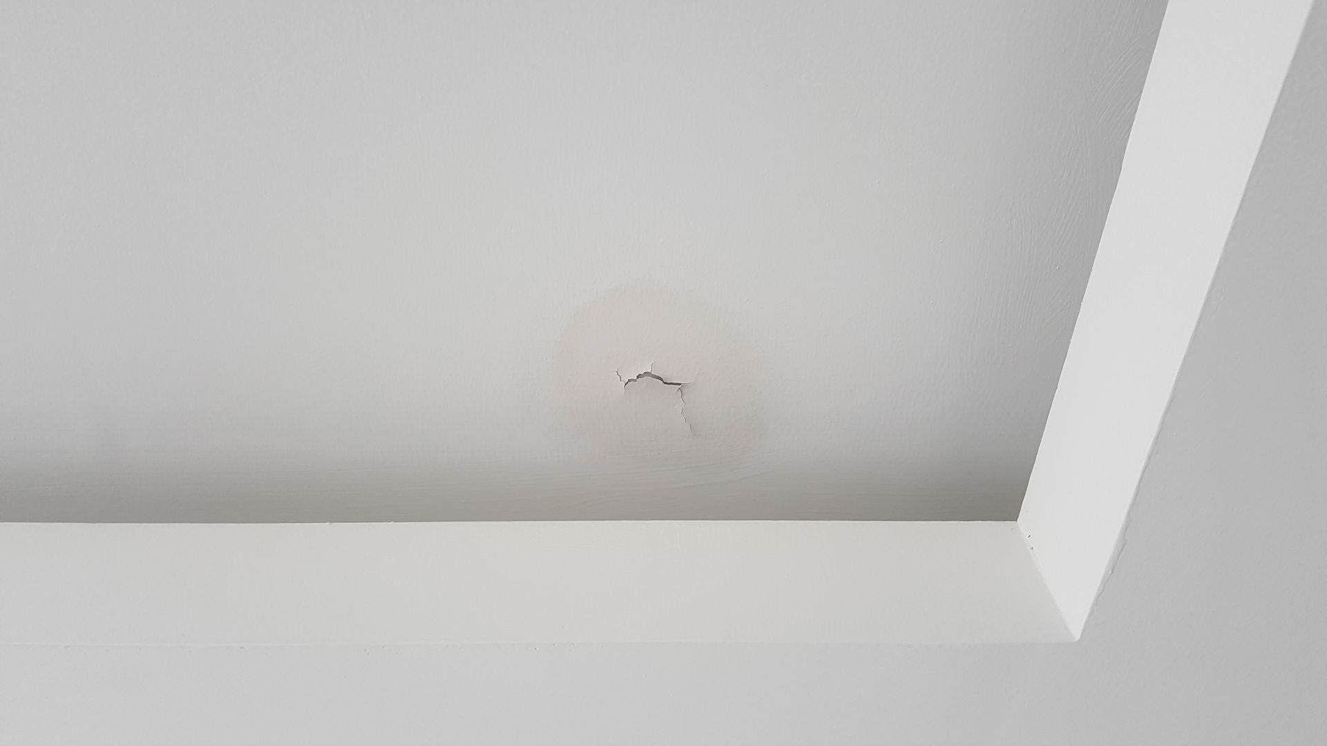 White ceiling with water damage stain and small holes.