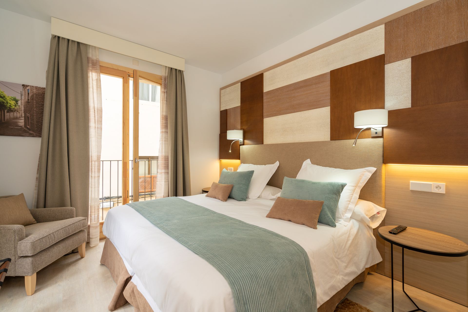 Hotelzimmer mit Kingsize-Bett, Balkon und Einrichtung in neutralen Farbtönen.