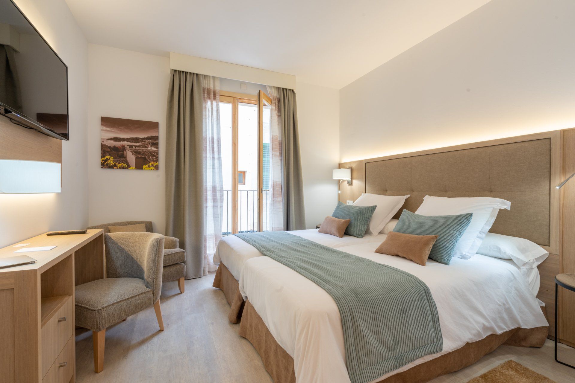 Hotel room with a king-size bed, balcony access, desk, and a chair, in neutral tones.