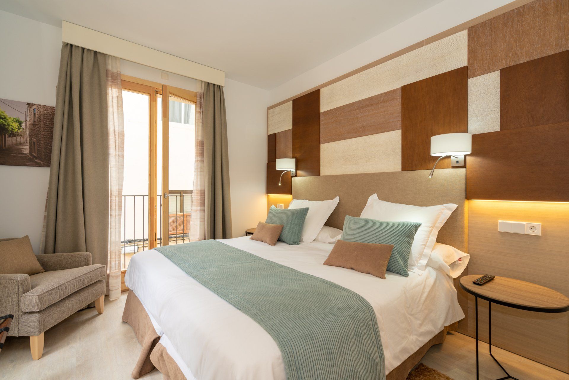 Hotel bedroom with a large bed, balcony, and neutral color decor.