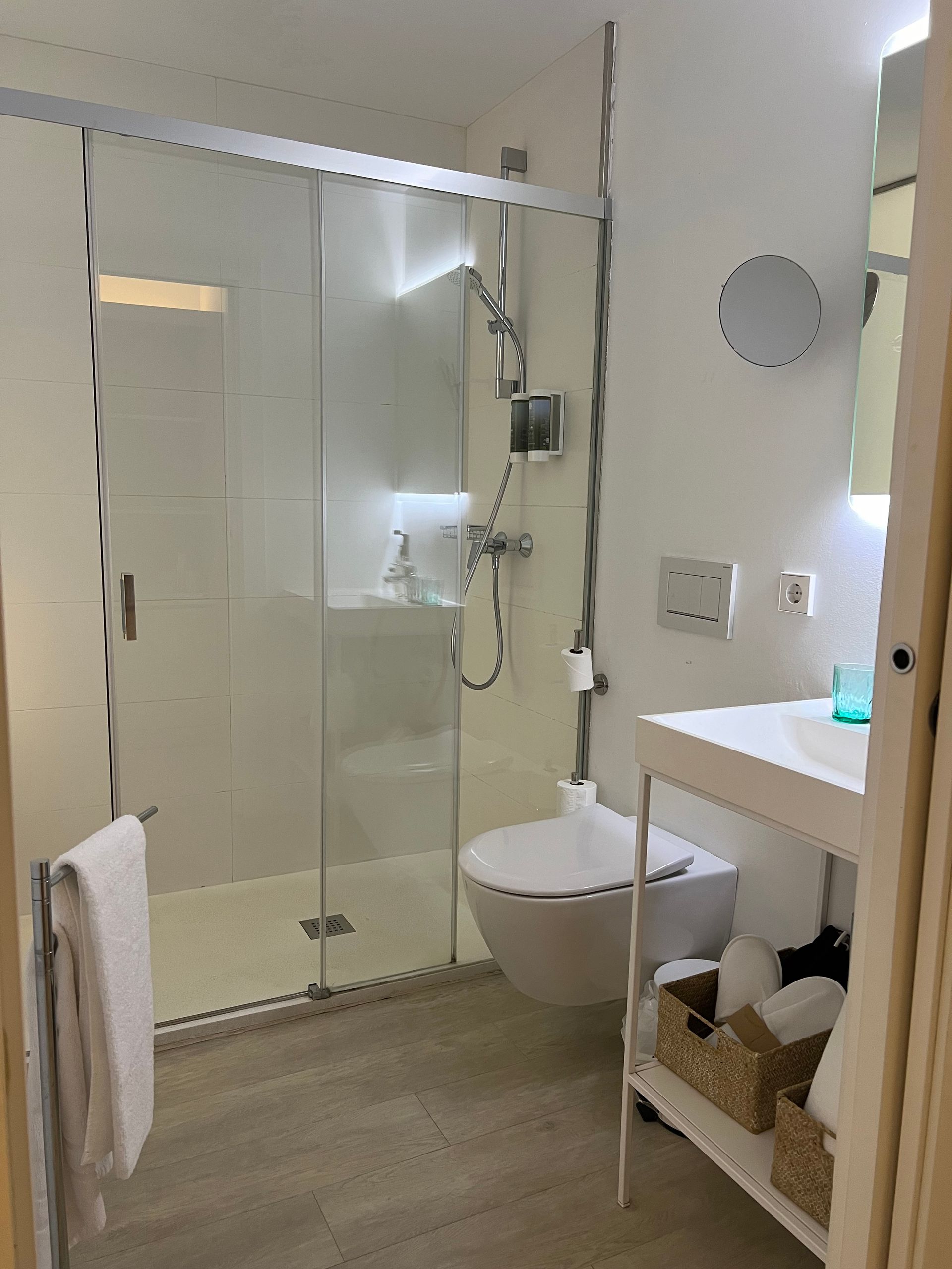 Bathroom with glass shower, toilet, sink, and towels. Neutral tones, modern design.