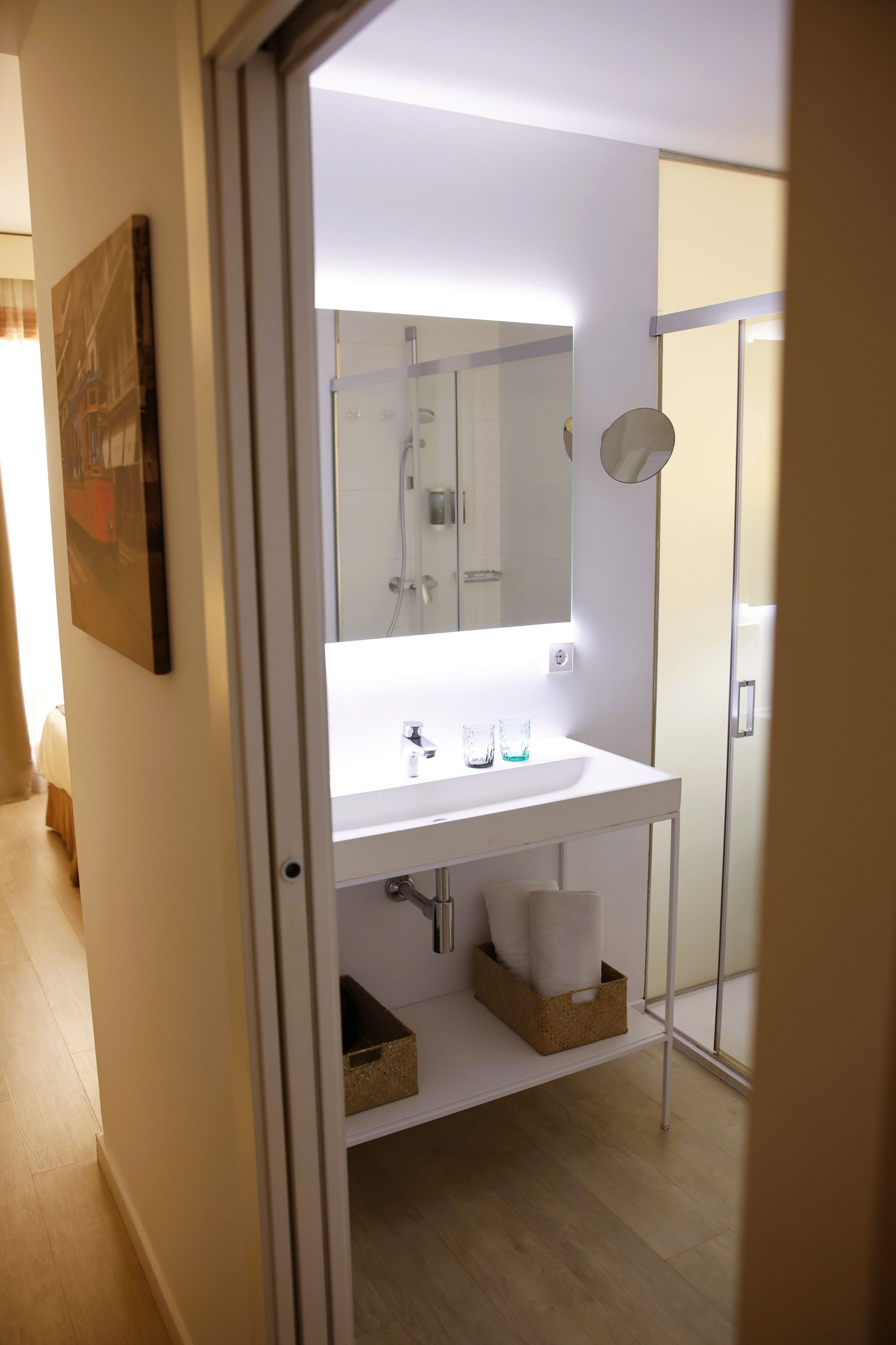 Bathroom with white sink, large mirror, glass shower, and open shelving.