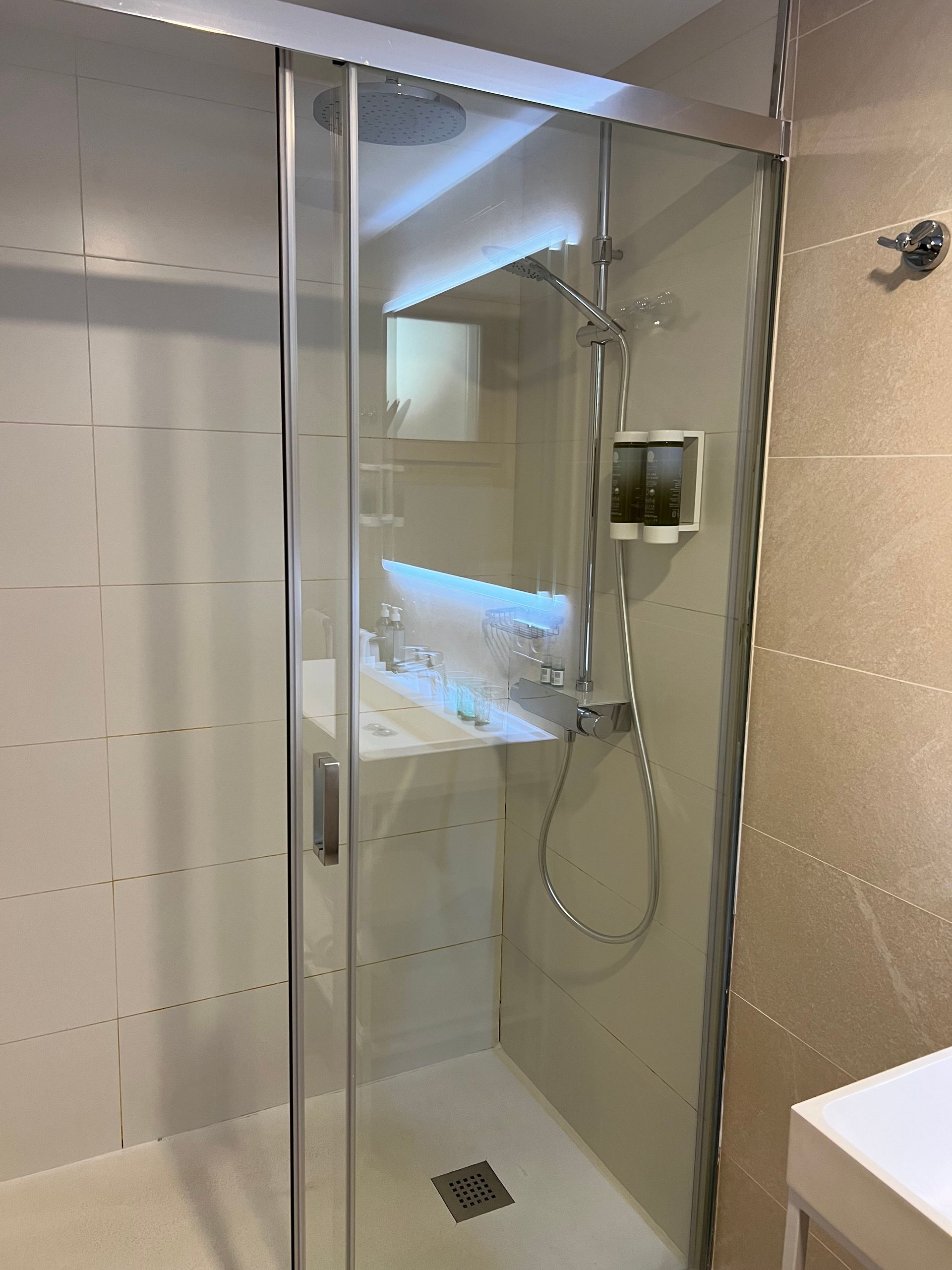 A shower enclosure with a sliding glass door and a rainfall showerhead in a modern bathroom.
