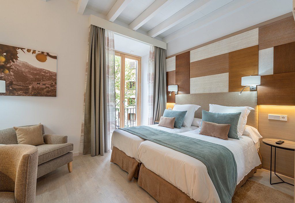 Habitación de hotel con dos camas, un pequeño sofá y una ventana con vista