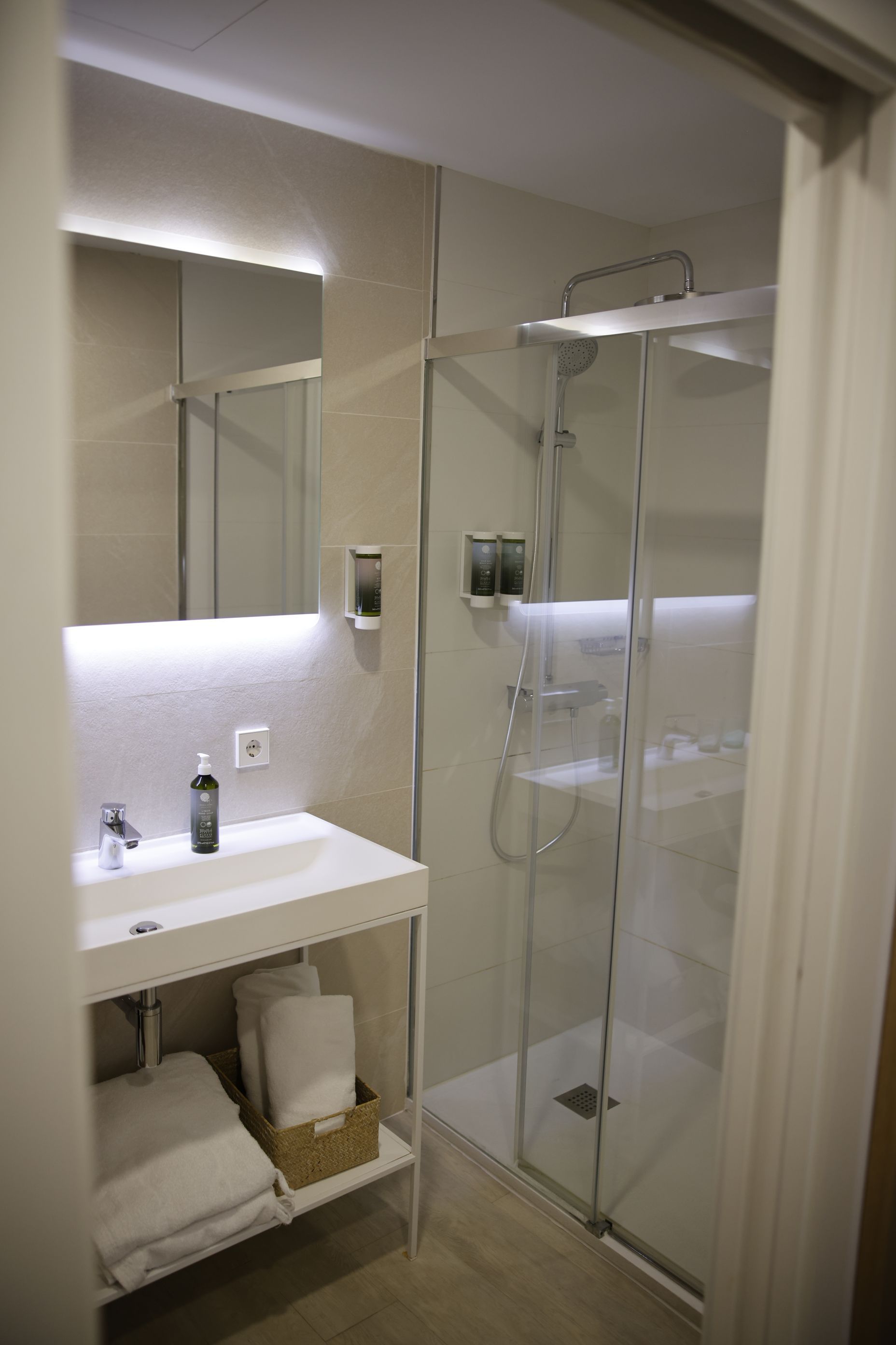 Modern bathroom with a walk-in shower, white sink, and towels.