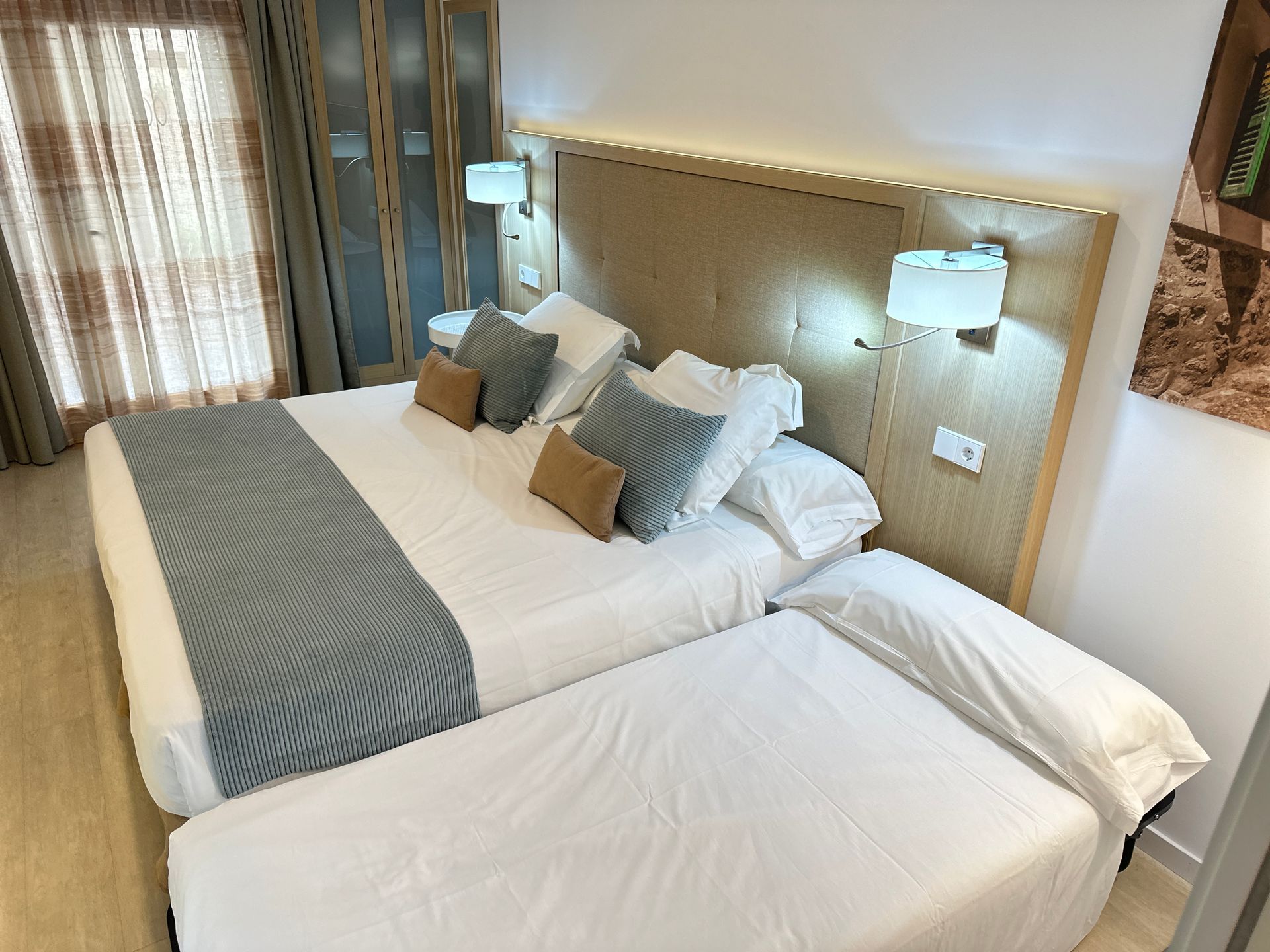 Hotel bedroom with large bed, blue and tan bedding, and a smaller pull-out bed.