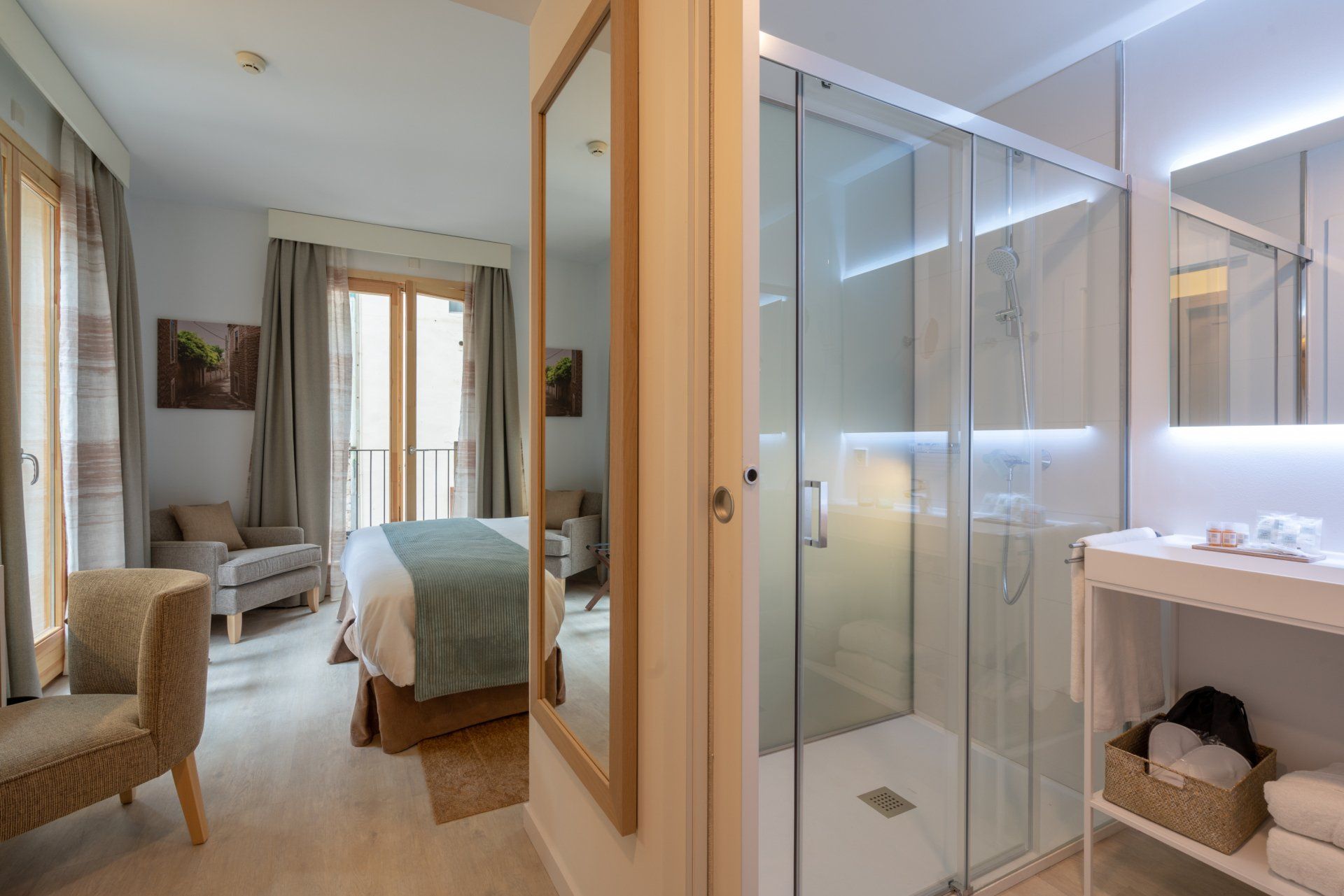 Chambre et salle de bain avec douche en verre, planchers de bois clair et tons neutres.