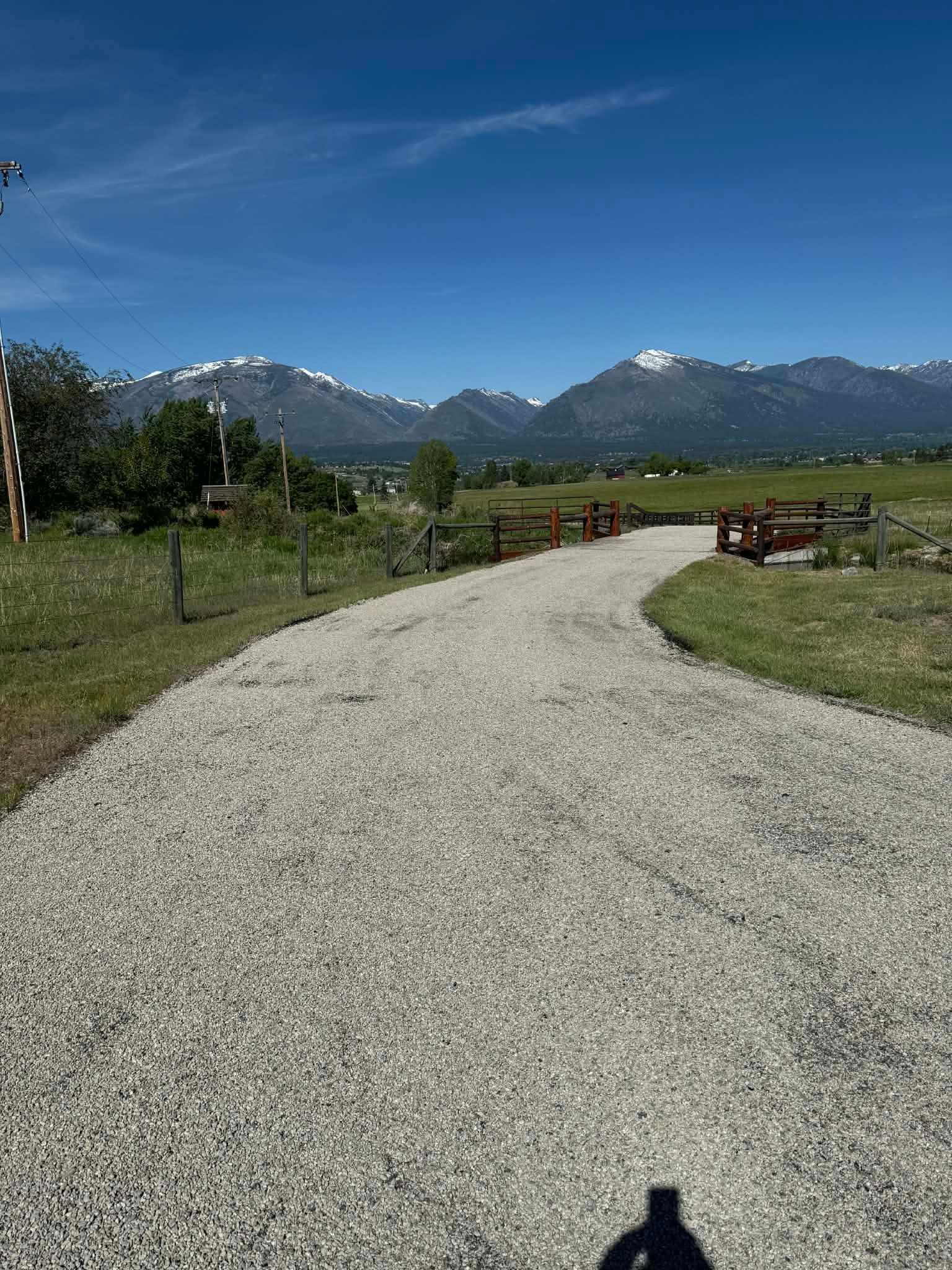 Curved chip seal driveway installation on a rural property with mountain views in Great Falls, Montana