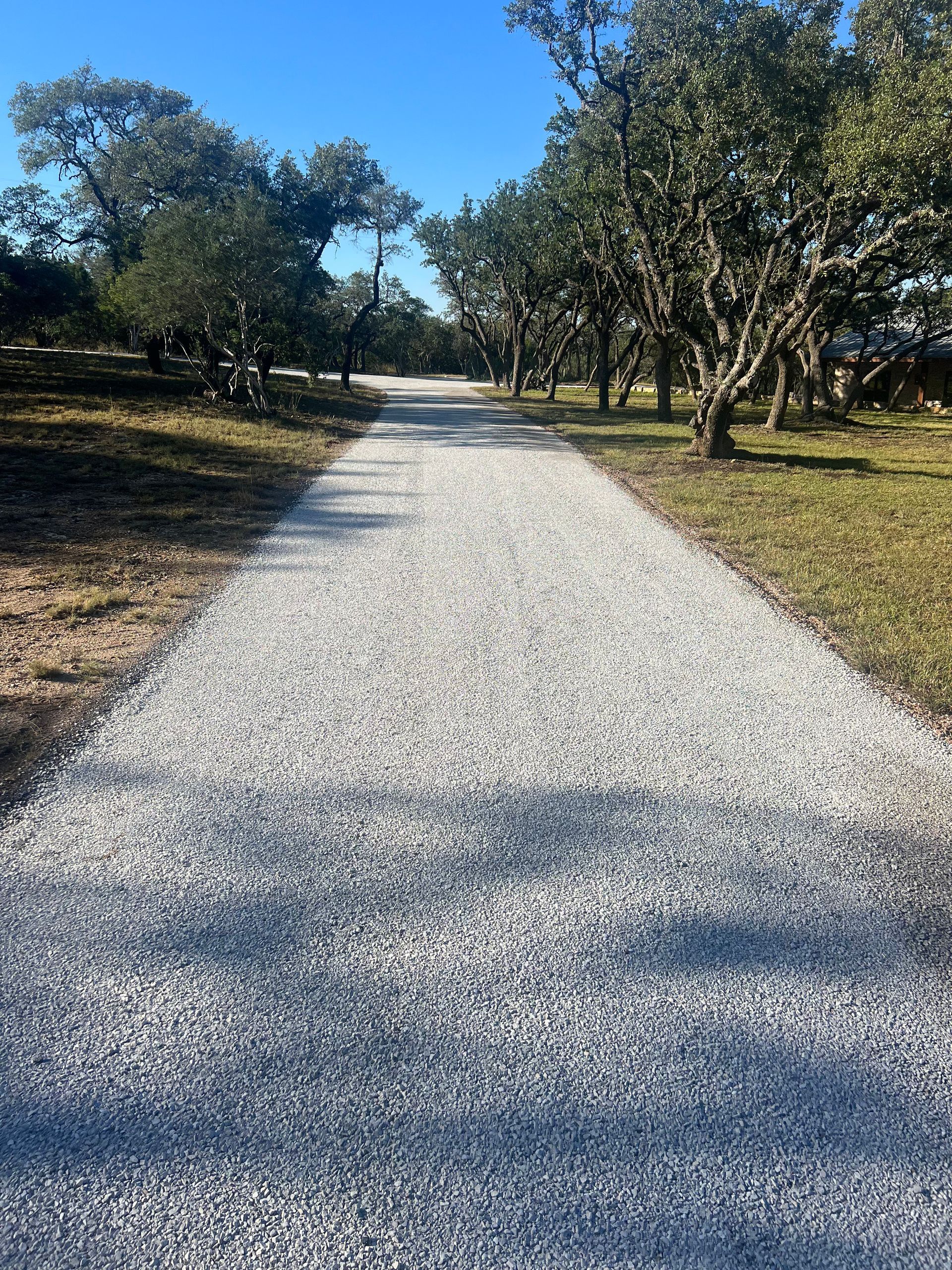 Fresh chip seal driveway installation on a tree-lined residential road in Great Falls, Montana