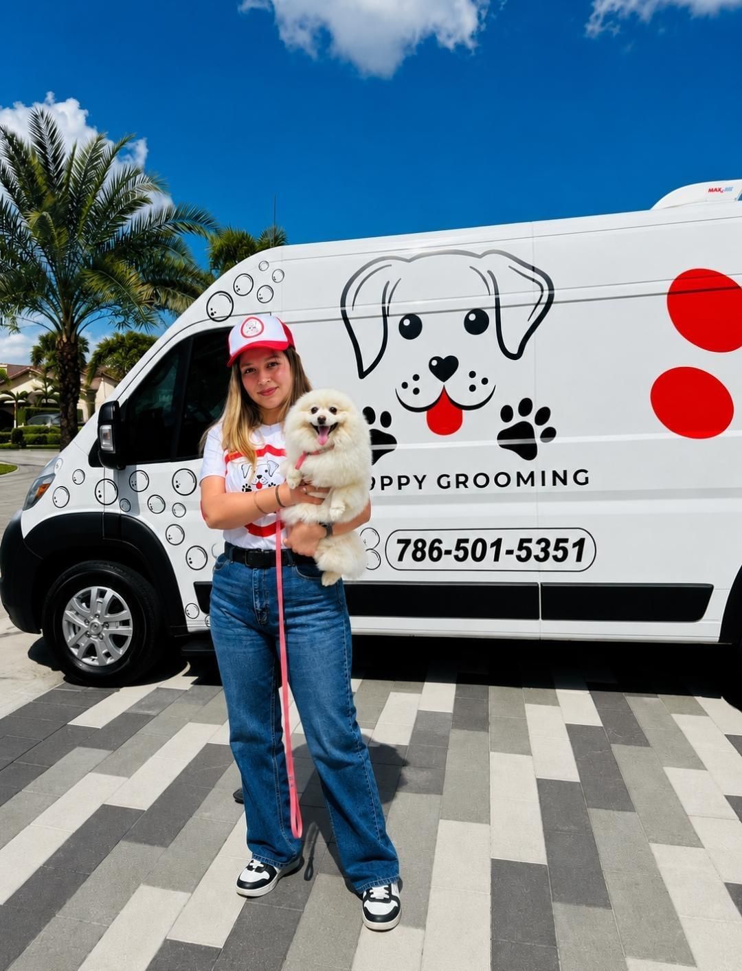 Snoopy Grooming groomer holding a freshly groomed Pomeranian in front of the Snoopy Grooming van