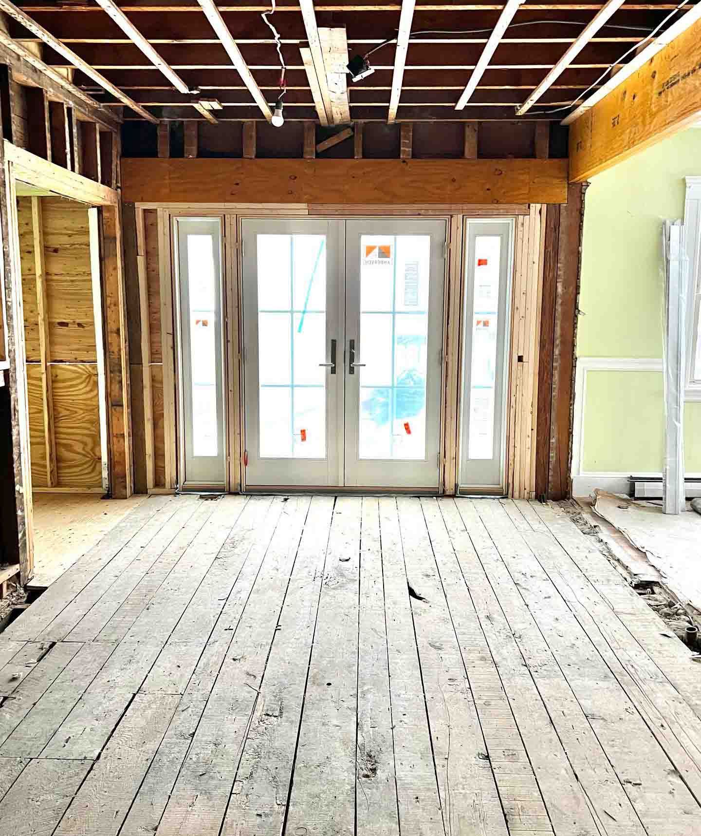 An empty room with a wooden floor and sliding glass doors.