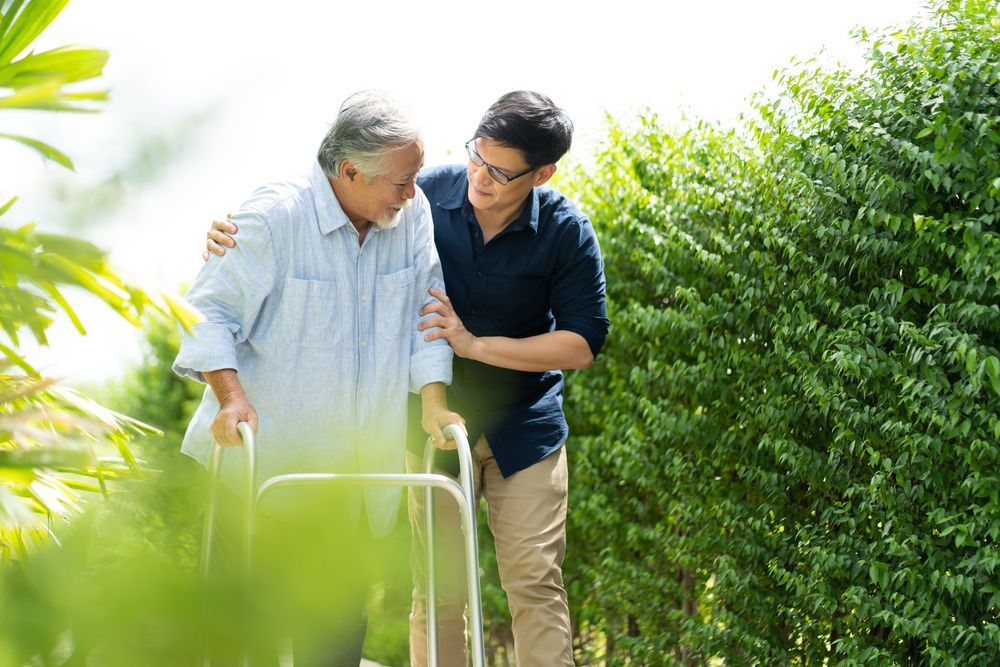 Two People Walking Beside an Elderly Man Using a Walker — XL Care in Ayr, QLD
