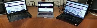 three laptops are sitting on a wooden table .