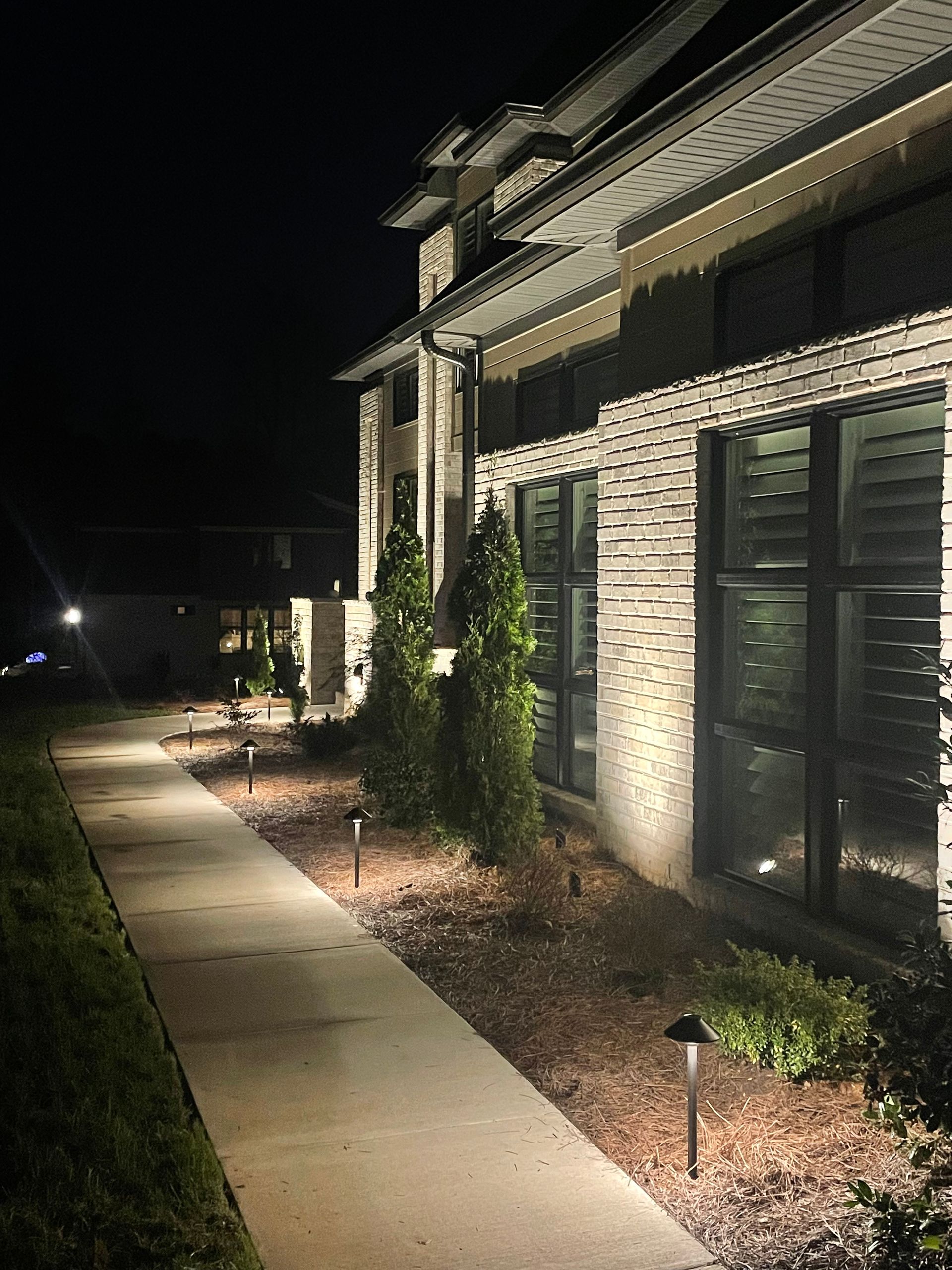 Pathway with landscape lighting alongside a building at night.