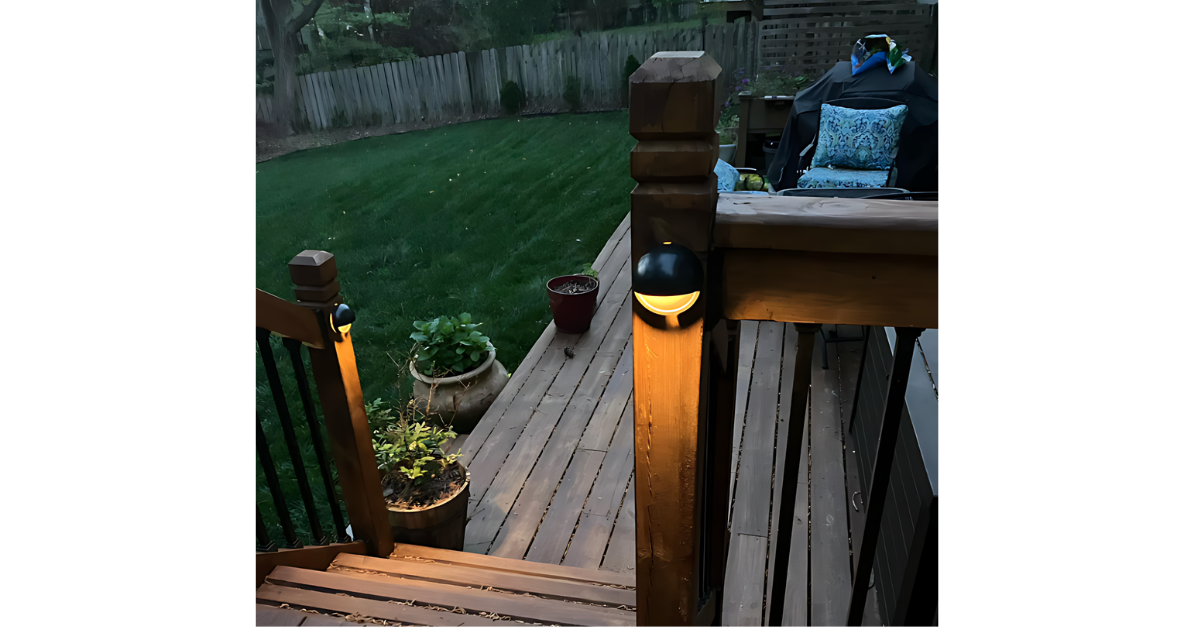 Wooden deck with built-in lights, looking out to a backyard with a fence.