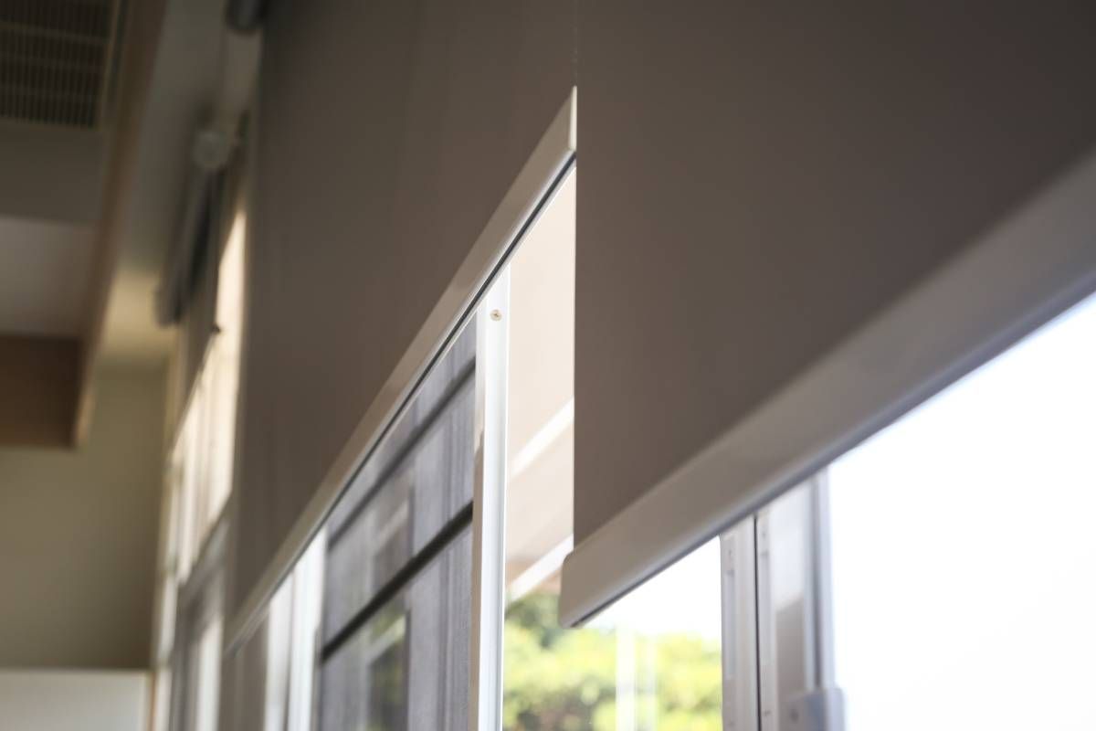 A close-up of the best motorized window shades mid-opening on large windows in a home.