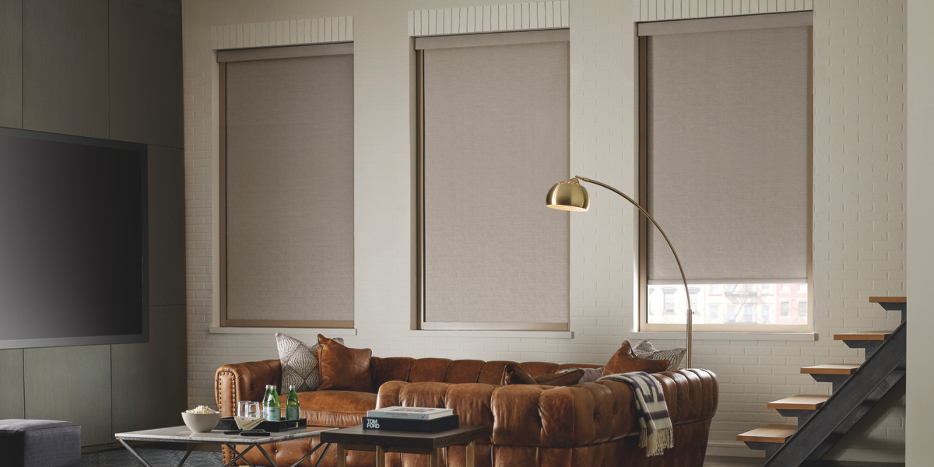 Room-darkening roller shades from Hunter Douglas on tall windows in a chic living room