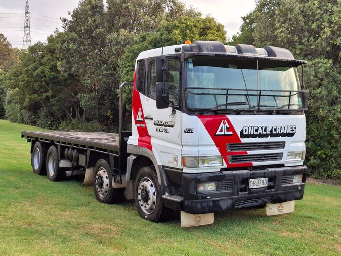 A red and white flatbed truck is parked in a grassy field.