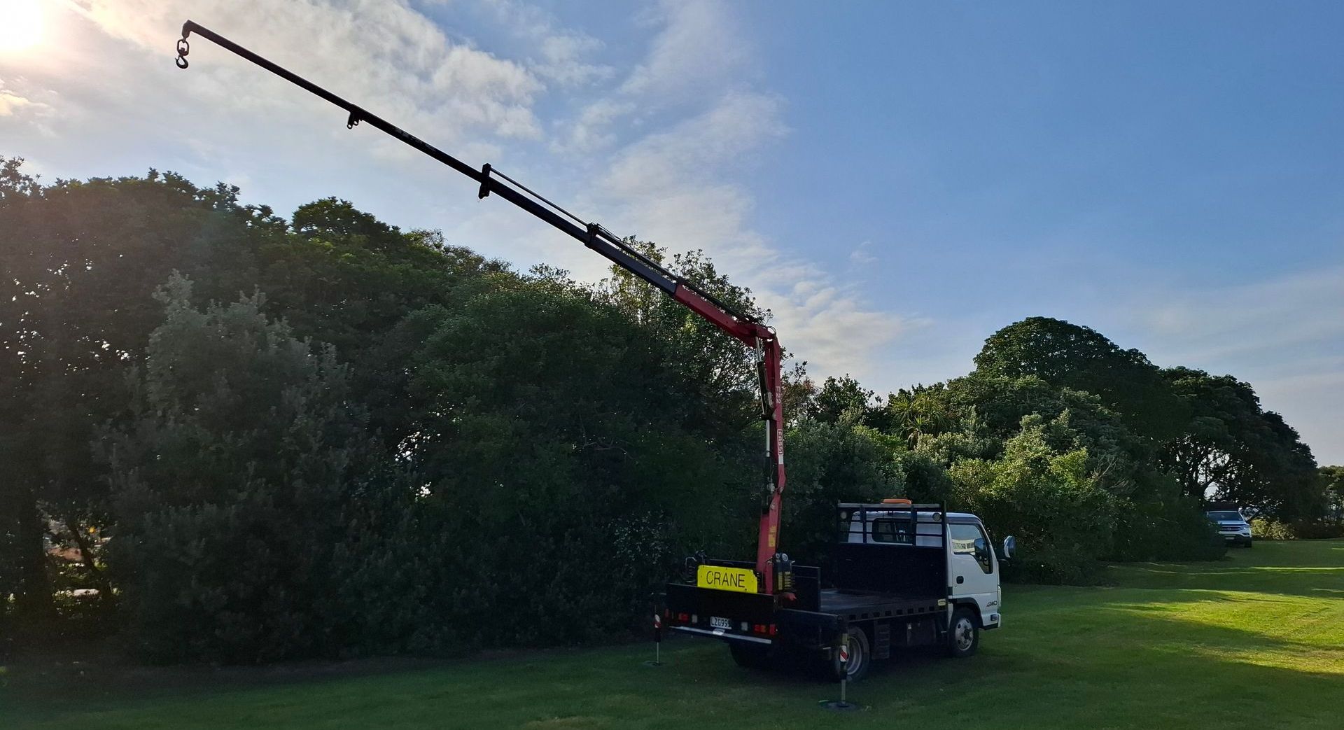 A crane is attached to the back of a truck in a field.
