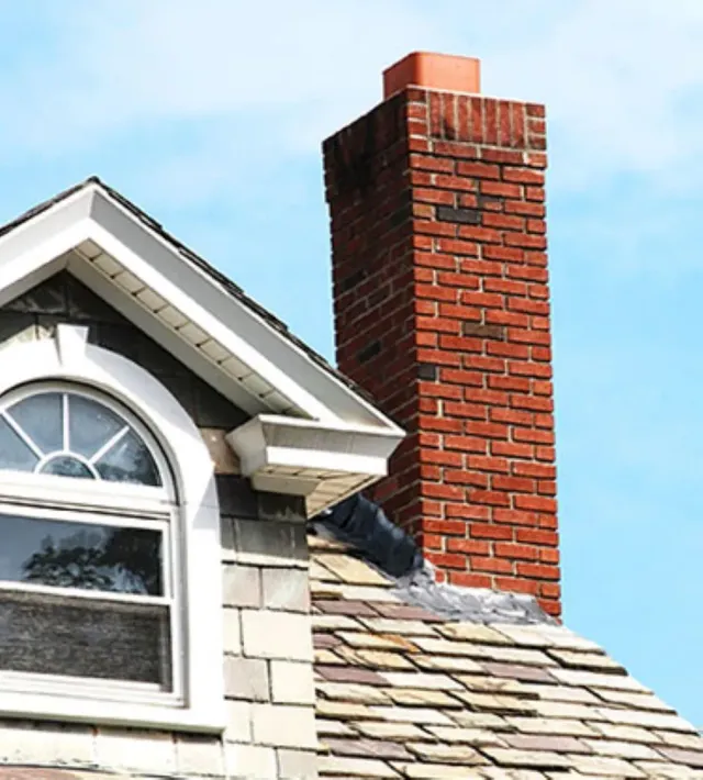 A brick chimney is on the roof of a house