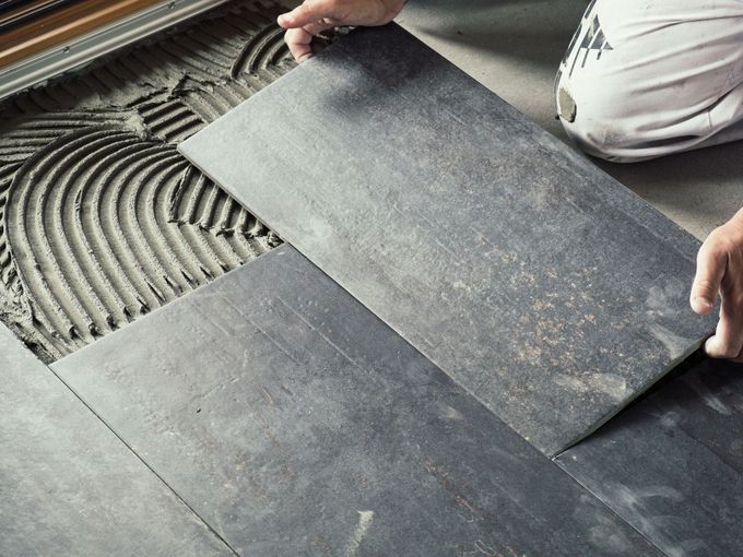 A person is laying a tile on the floor.