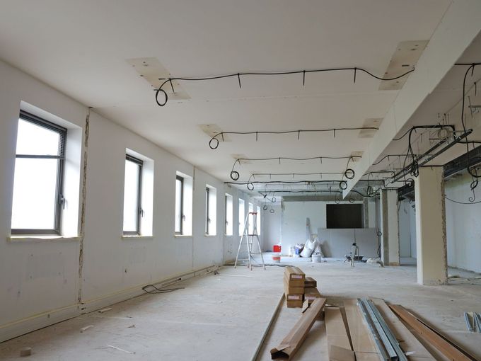 A large room with a lot of windows and a lot of wires hanging from the ceiling.