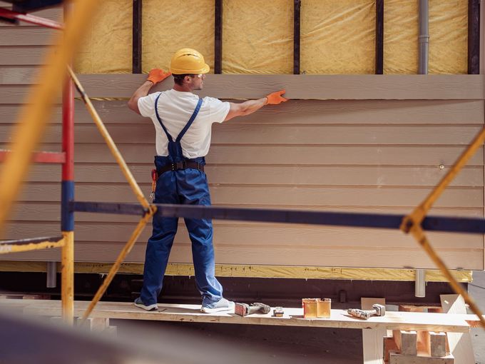 A construction worker is installing siding on a building.