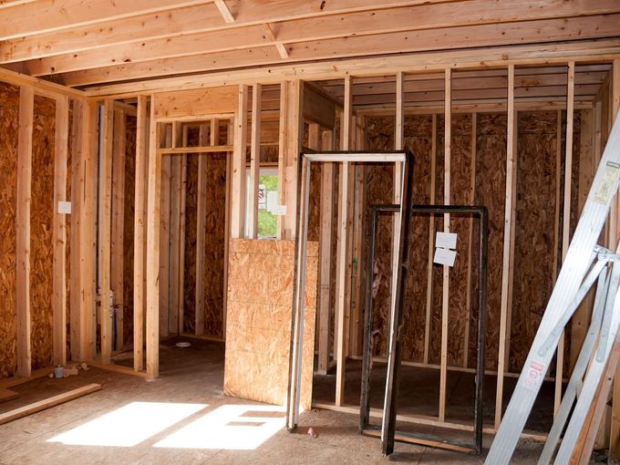 A room in a house under construction with wooden beams and a door.