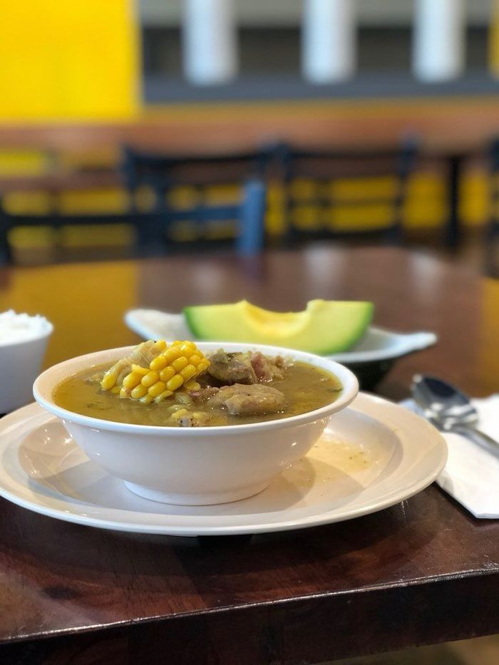 A bowl of soup is sitting on a plate on a table.