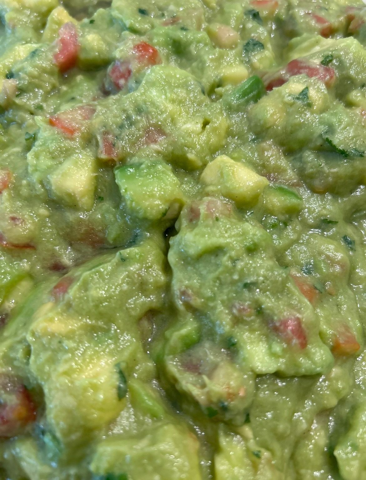 A buffet with a variety of food including guacamole and tomatoes