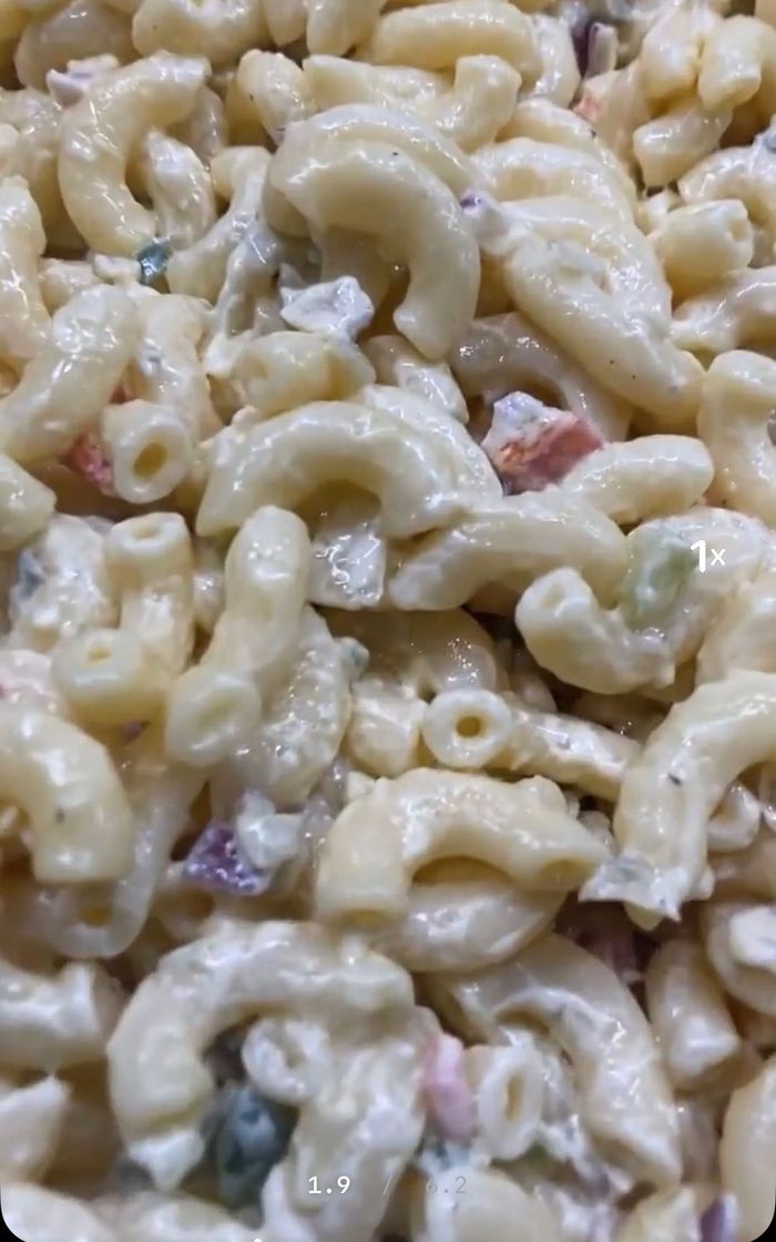 A close up of a macaroni salad with vegetables in a bowl.