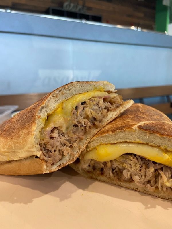 A sandwich with meat and cheese is cut in half on a plate.