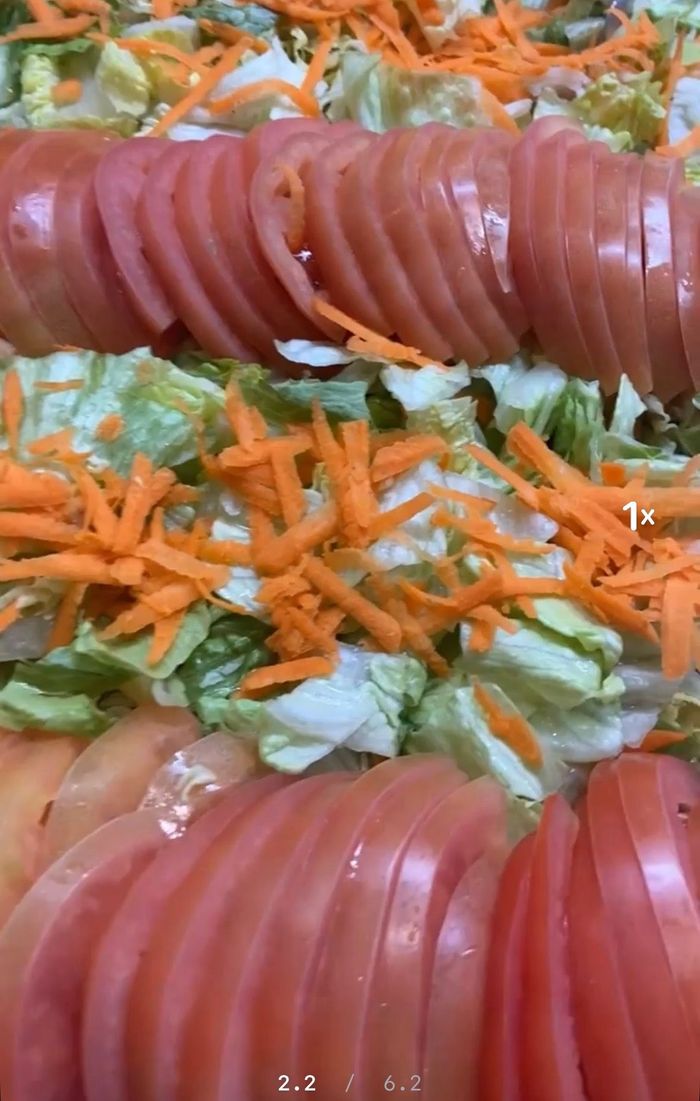 A close up of a salad with tomatoes , lettuce and carrots.