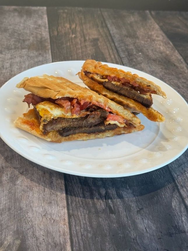 Two sandwiches are on a white plate on a wooden table.