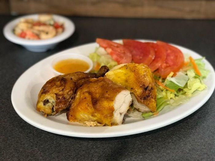 A white plate topped with chicken and vegetables on a table.