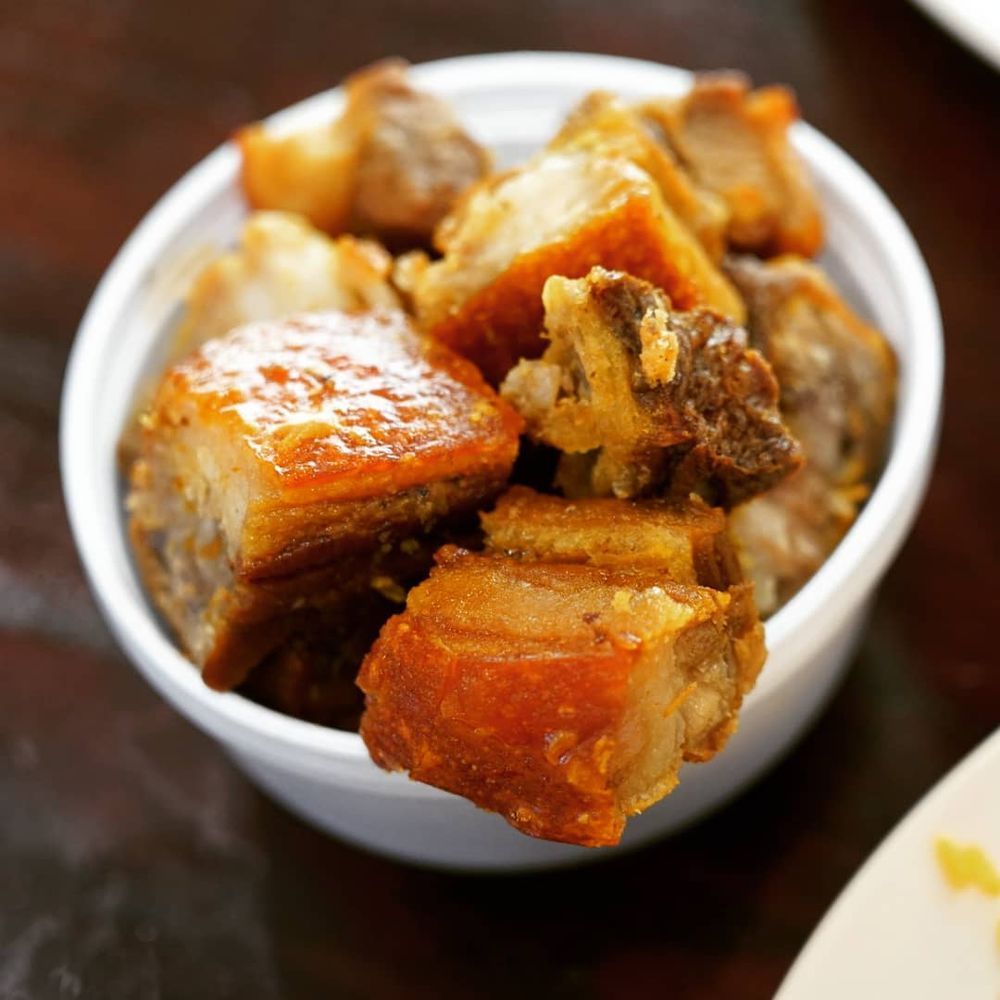 A bowl of fried pork is sitting on a table.