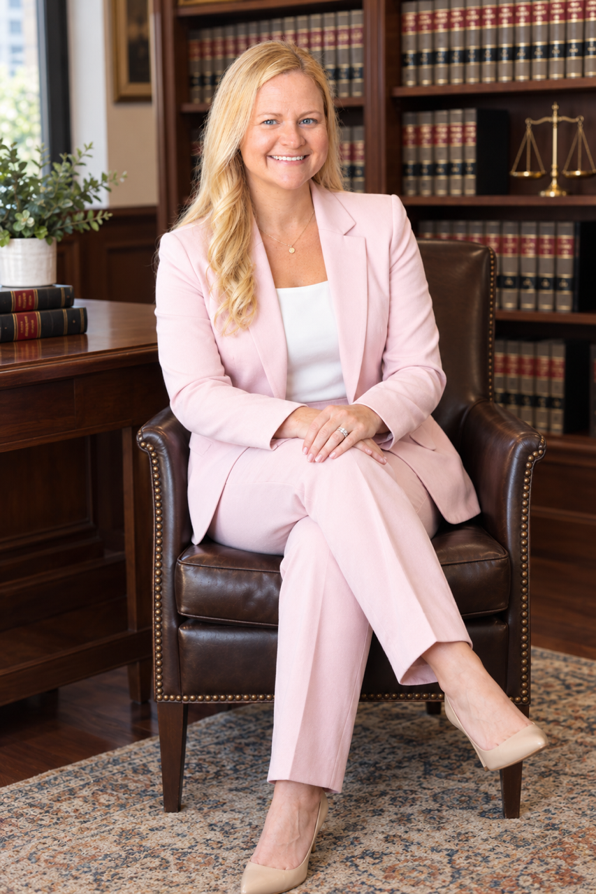 Laura Pendry. A woman sitting in a chair wearing a light pink suit.