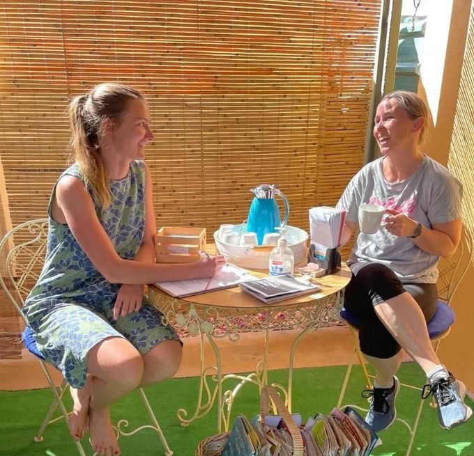 Two Women Are Sitting At A Table Drinking Coffee — Aloha Therapeutic Massage In Gillen, NT