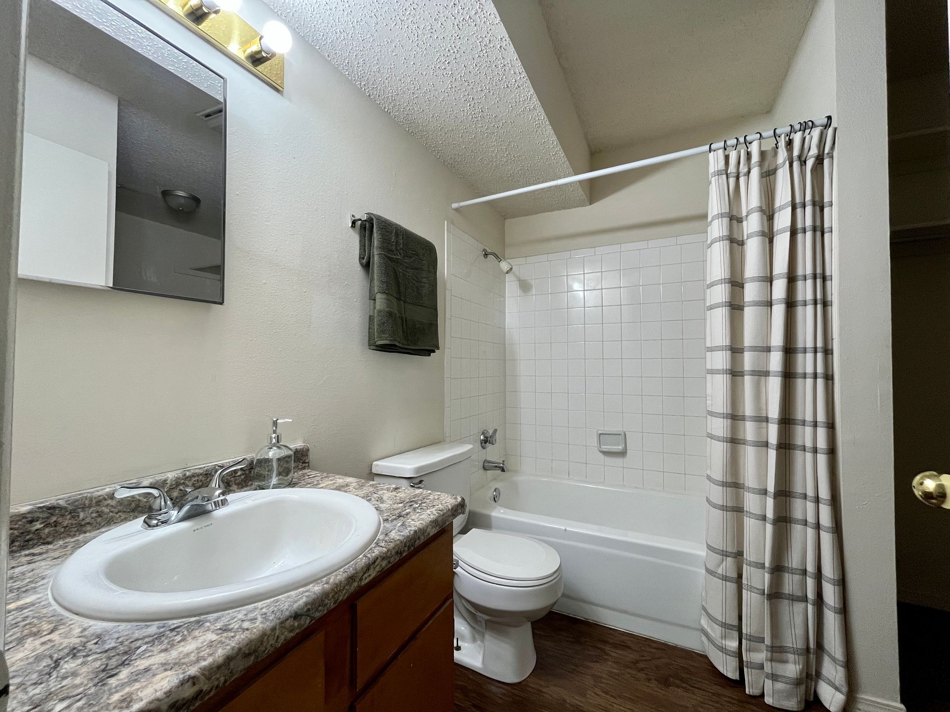 Fort Smith apartment bathroom with vanity countertop, white tile tub/shower combo, and striped curtain